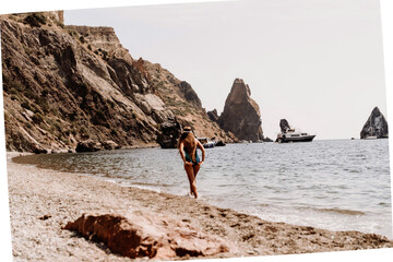 Woman beach vacation photo. A happy tourist in a blue bikini enjoying the scenic view of the sea and volcanic mountains while taking pictures to capture the memories of her travel adventure.