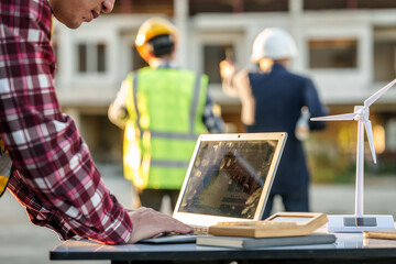engineers discussing a solar energy project with a small solar panel model on the table, a laptop,...