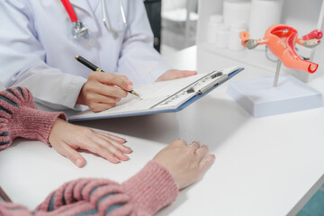 female doctor reassuring patient with comforting hand gesture, with model of the female...