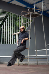 An Asian female model stands confidently on a tennis court, dressed in jeans and a black shirt, adorned with a bandana and glasses