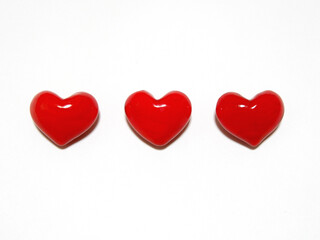 3 pieces three-dimensional glossy hearts lined up horizontally on white background.