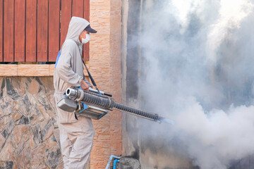 Outdoor healthcare worker using fogging machine spraying chemical to removal mosquitoes and control...
