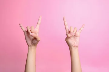 Foto op Plexiglas Two hands showing rock sign, rock and roll sign hand gesture isolated over pink background © Queenmoonlite Studio