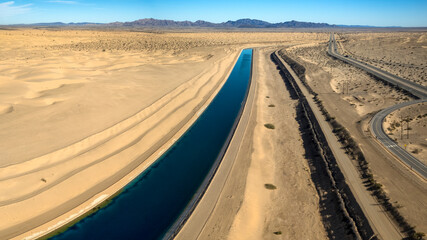 Dramatic aerial view of the all-American canal traveling through the Buttercup sand dunes in imperial county California. - obrazy, fototapety, plakaty