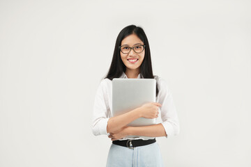 An Asian woman smiles confidently while hugging her laptop, showcasing warmth and professionalism in a bright, modern setting.