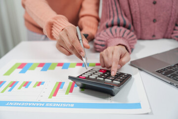 two individuals are engaged in accounting work. One person is wearing a pink sweater, and they both...