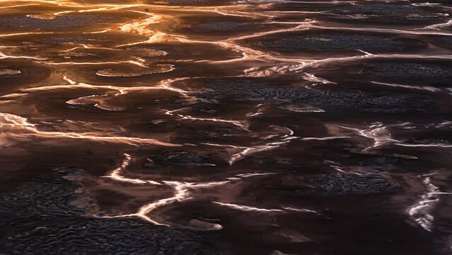 Aerial parallax around braided streams of water between large mounds, natural earth wasteland textured pattern