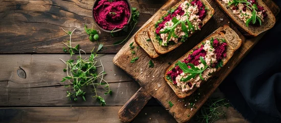Keuken spatwand met foto Top view of homemade rye bread sandwiches with beetroot hummus and herbs on a cutting board © 2rogan