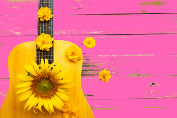 yellow flowers sunflowers, cosmos on guitar arrangement flat lay postcard style on background pink wooden