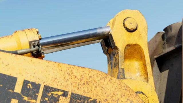 Hydraulic arm of digger moving bucket loader while working on construction site, close up
