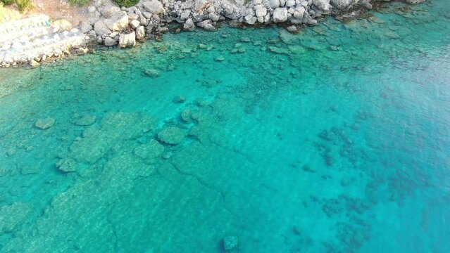 Drone view in Greece top view over blue sea in Loutro next to a rocky hill on a sunny day