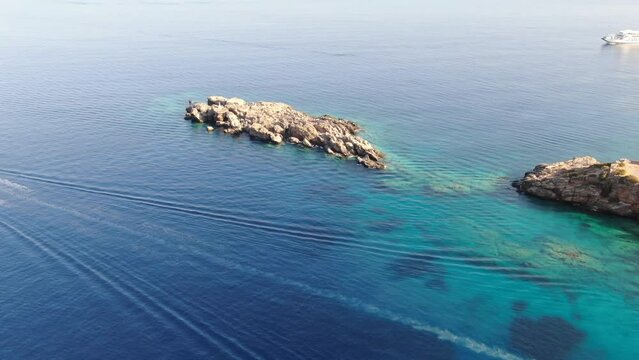 Drone view in Greece flying over blue sea in Loutro with rocks on the water on a sunny day