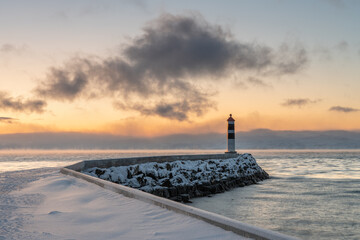 Beacon at the end of a breakwater with beautiful light of the polar night in the background on a...