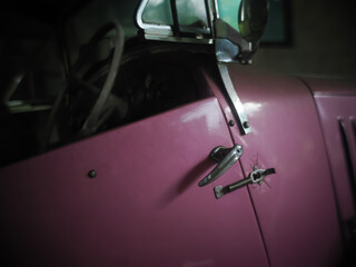 Close-up of car handle of a pink shiny classic vintage car
