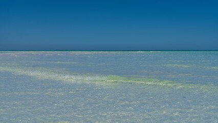 A beautiful aquamarine ocean with crystal clear water. The waves are foaming towards the shore. Blue sky. Copy space. Minimalism. Madagascar. Nosy Iranja 