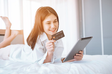 Young woman  lying in bed using mobile cell phone credit bank card shopping online rest relax spend...