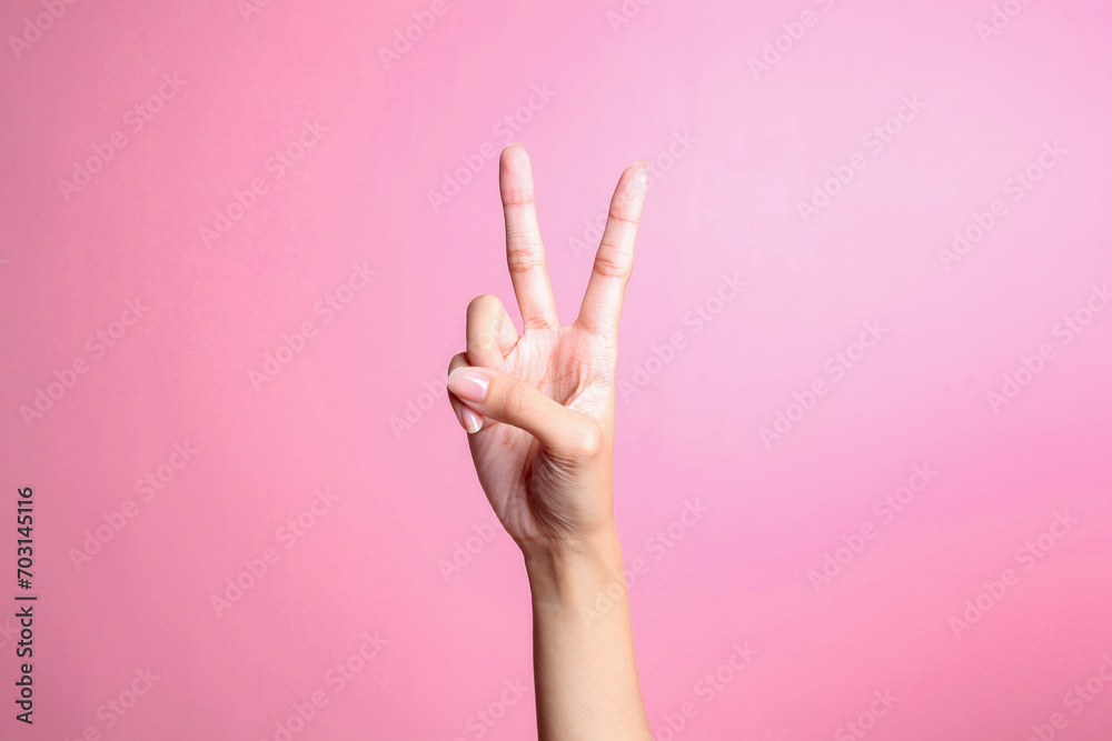 Wall mural Hand showing two fingers isolated on pink background, victory and peace gesture