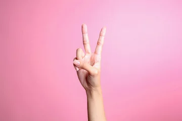 Fotobehang Hand showing two fingers isolated on pink background, victory and peace gesture © Queenmoonlite Studio