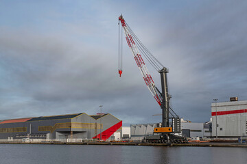 Crane, warehouse and hangar on a quay in the port of Saint-Nazaire in Brittany, France - obrazy, fototapety, plakaty