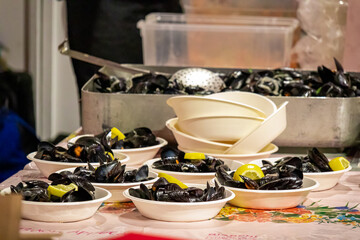 Table with several bowls of delicious exquisite Cozze mussels with lemon slice on top. Served...
