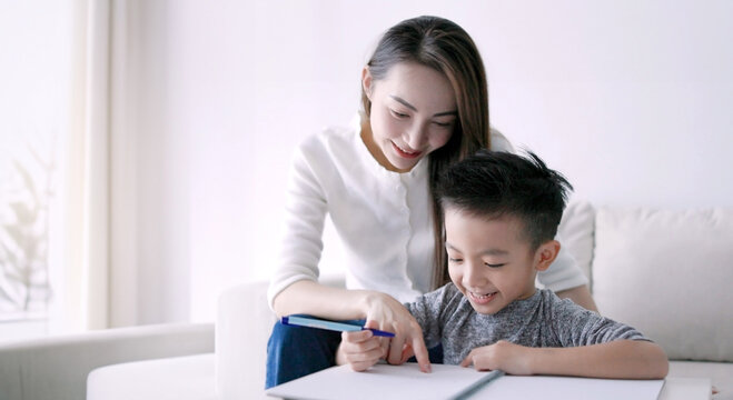 Young mother checking homework helping  child  with study at home