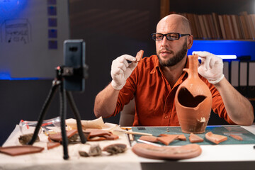 Archaeologist blogger presenting a live broadcast works late at night in the office telling...