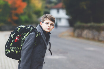 Happy kid boy with glasses and backpack or satchel. Schoolkid in stylish fashon coan on the way to...