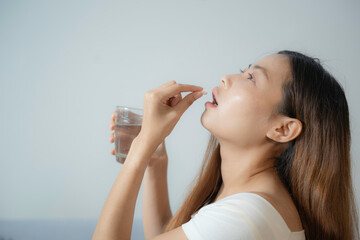 Young asian woman bend her head to back to taking pill easier with illness express on her eye and face on white background and copy space.