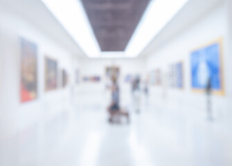 Blurred photo scene of art exhibition at gallery or museum with paintings and people, room...