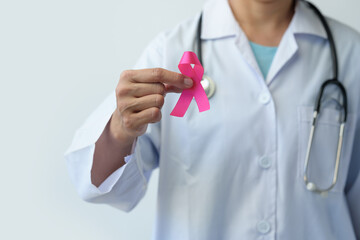 Breast cancer campaign Cropped image of woman's hand in doctor's uniform with pink ribbon in hospital showing fight To save lives and illnesses from cancer World cancer day concept, health insurance.
