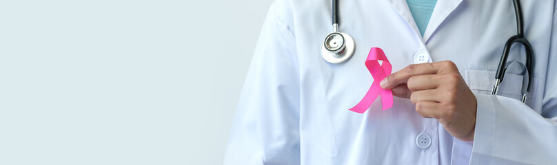 Breast cancer campaign Illustration of woman's hand in doctor's uniform and pink ribbon showing battle To save lives and illnesses World cancer day concept, insurance, copy space, banner, panorama. - obrazy, fototapety, plakaty