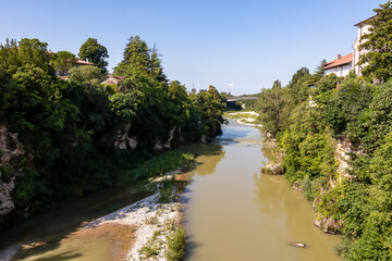 Obraz premium Scenic view from bridge Ponte del Diavolo in town of Cividale del Friuli, Udine province, Friuli Venezia Giulia, Italy. Idyllic atmosphere along banks of serene Natisone river. UNESCO World Heritage
