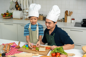 Happy moment asian father and son cooking breakfast in the kitchen. Dad and child asian family having fun preparing food bread egg sandwich. Positive parent and kid nice relationship