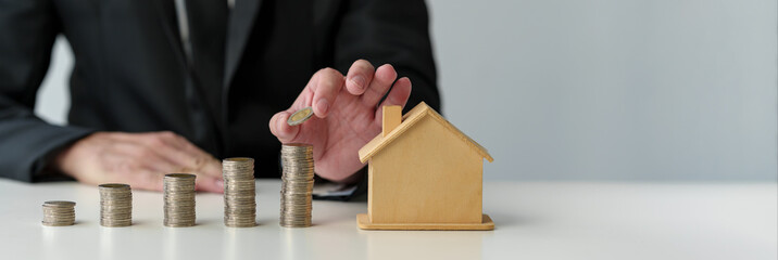 Businessman holds stacked coins to plan home purchase Concept of saving money for financial...
