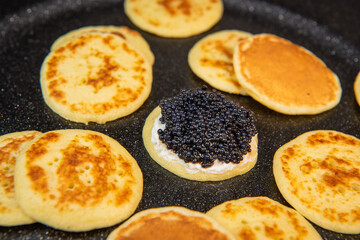 Blinis with black caviar and cream cheese, on a festive dish, mini pancakes, an elegant appetizer,...