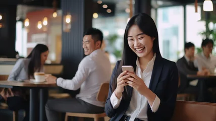 Fotobehang Smiling woman using mobile phone sitting in coffee bar © wiparat
