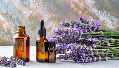 Obraz na płótnie Canvas Essential oil bottles for aromatherapy, holistic medicine, or fragrance, accompanied by a bunch of fragrant lavender, set against a soft abstract backdrop. Side view, close-up