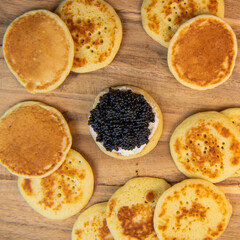 Blinis with black caviar and cream cheese, on a festive dish, mini pancakes, an elegant appetizer,...