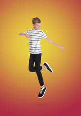 Fototapeta na wymiar Teenage boy jumping on color gradient background