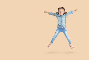Fototapeta na wymiar Cute girl jumping on beige background, space for text
