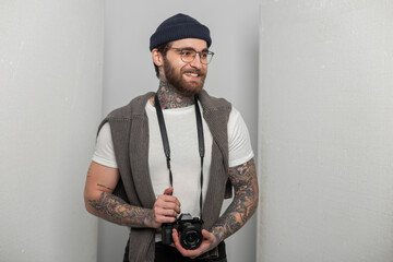 Happy handsome professional photographer man with smile with tattoo with knitted hat and sweater...