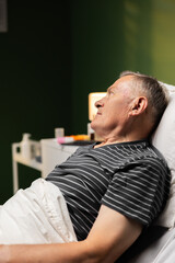 A senior patient lies back, a hint of weariness on his face, but a determined spirit for a swift recovery.