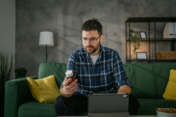 One man hold medicine drugs bottle pills read label on digital tablet