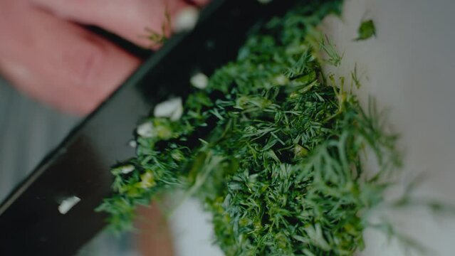 Chopped dill on a knife blade, highlighting the texture and freshness of the herb. Ideal for a stock video clip on culinary arts, ingredient preparation, and healthy cooking.