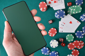 Online casino games concept with hand holding mobile and objects