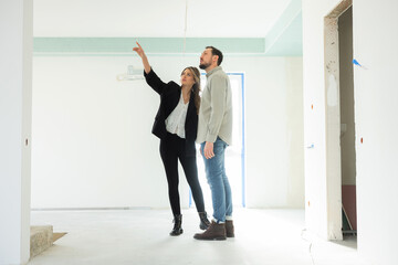 Delighted woman and man standing in the middle of new house discussing all aspects choosing new house.