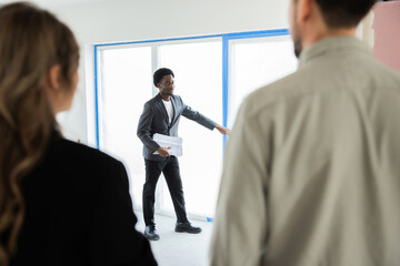 Picture of a focused, busy, dark-skinned African American real estate agent standing inside the new...