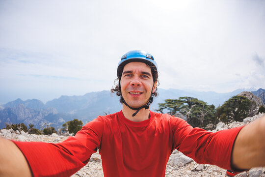 male climber in a helmet takes a selfie photo with the mountains. rock climbing and mountaineering
