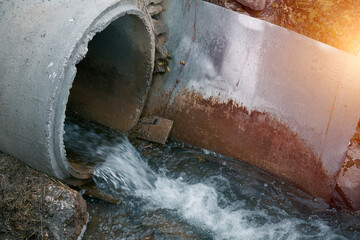 A sewage pipe drains toxic wastewater into a river, causing environmental pollution and ecological damage.
