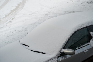 A Frozen Car Windshield Covered with Snowflakes in a Winter Storm. A Close-Up of a Car Windshield with Ice and Snow Flakes in a Winter Countryside.